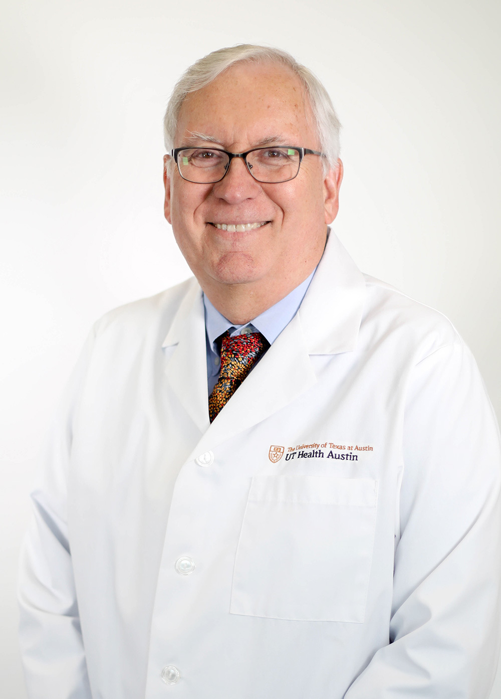 Pediatric neurologist Steve Roach, MD, wearing a white coat and smiling in front of a white backdrop.