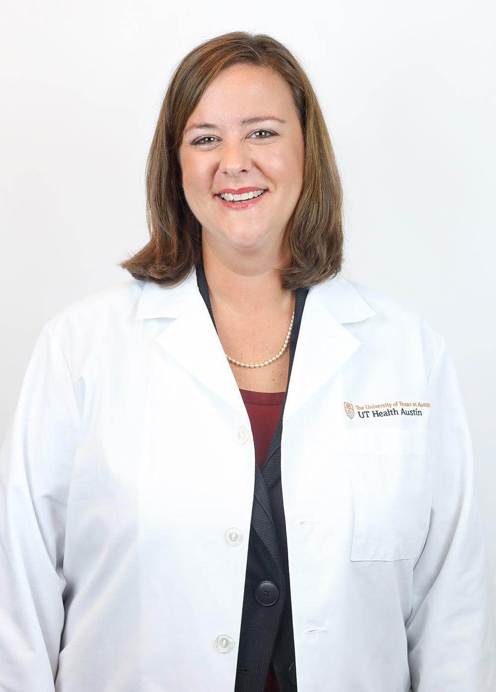 Female pelvic medicine and reconstructive surgeon Amanda White, MD, wearing a white coat and smiling in front of a white backdrop.